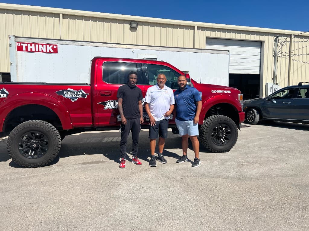 C & D Dent Guys team standing in front of branded red truck at the shop