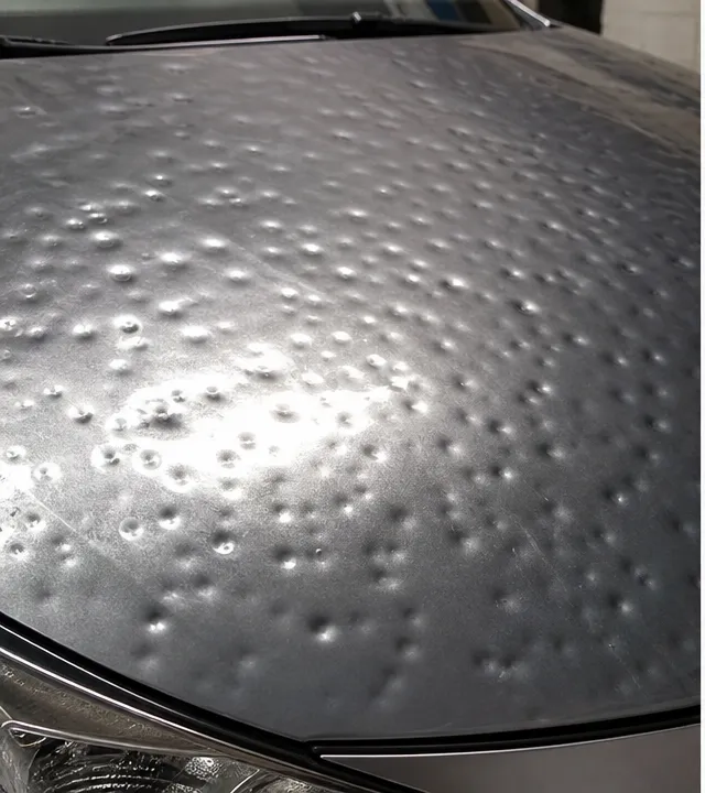 Before paintless dent repair — visible dent on hood panel